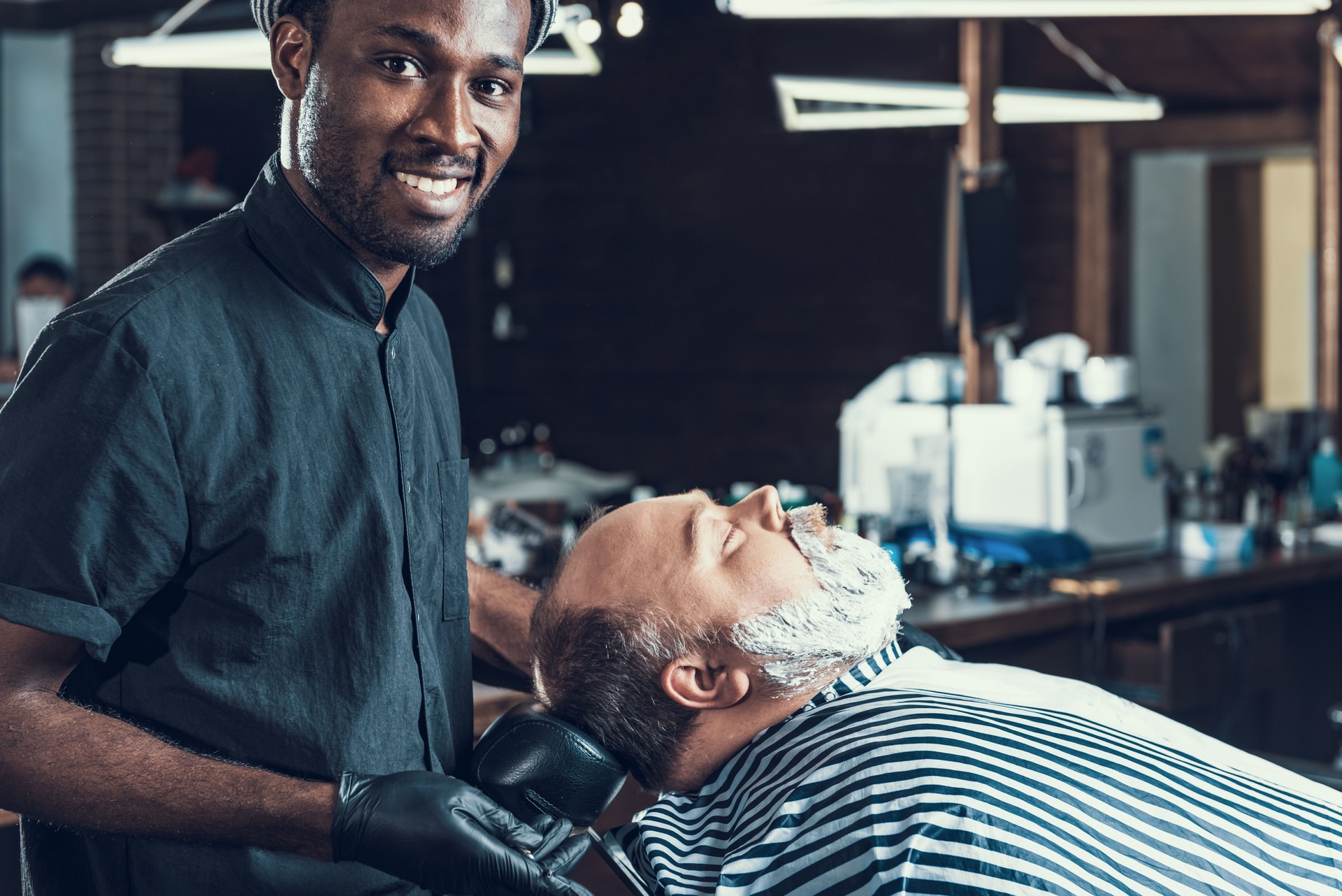 Barber master standing near client and smiling
