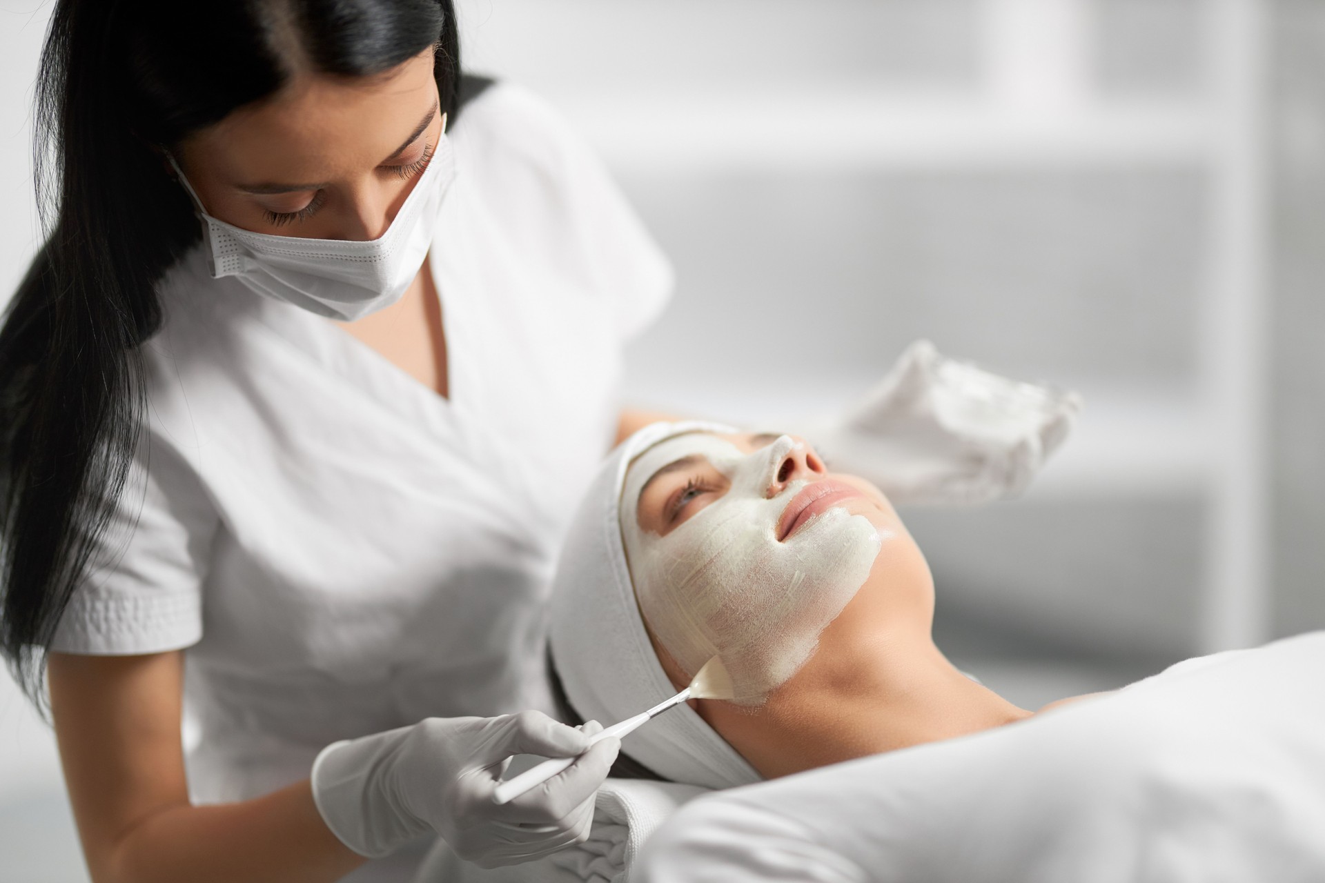 Beautician applying special white cream for patient.